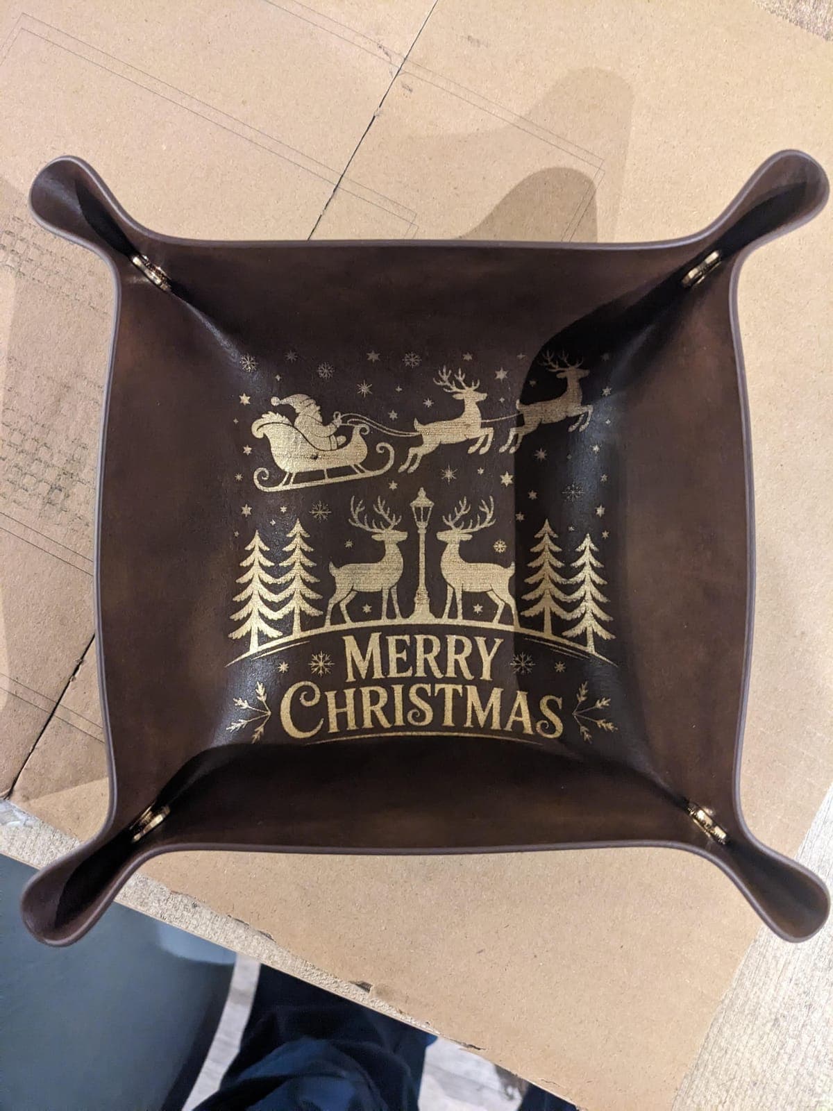 A brown valet tray engraved in gold with Santa's sleigh, reindeer and Merry Christmas
