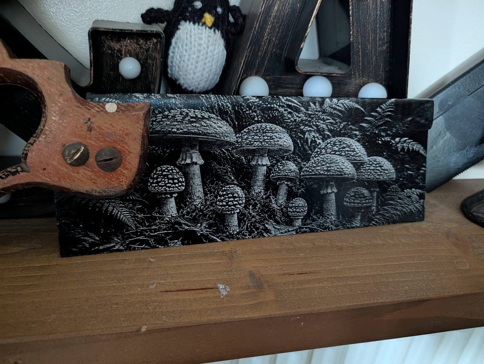 A woodland of toadstools engraved along an old hand saw