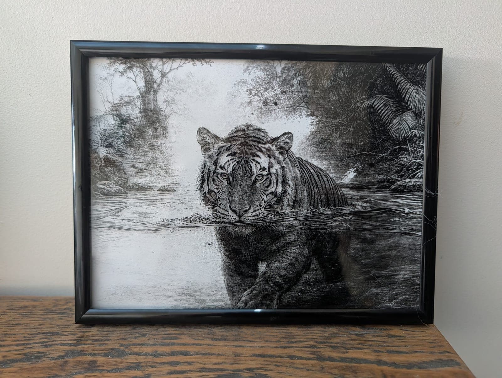 A black and white tiger wading through a jungle river, engraved on painted glass and framed