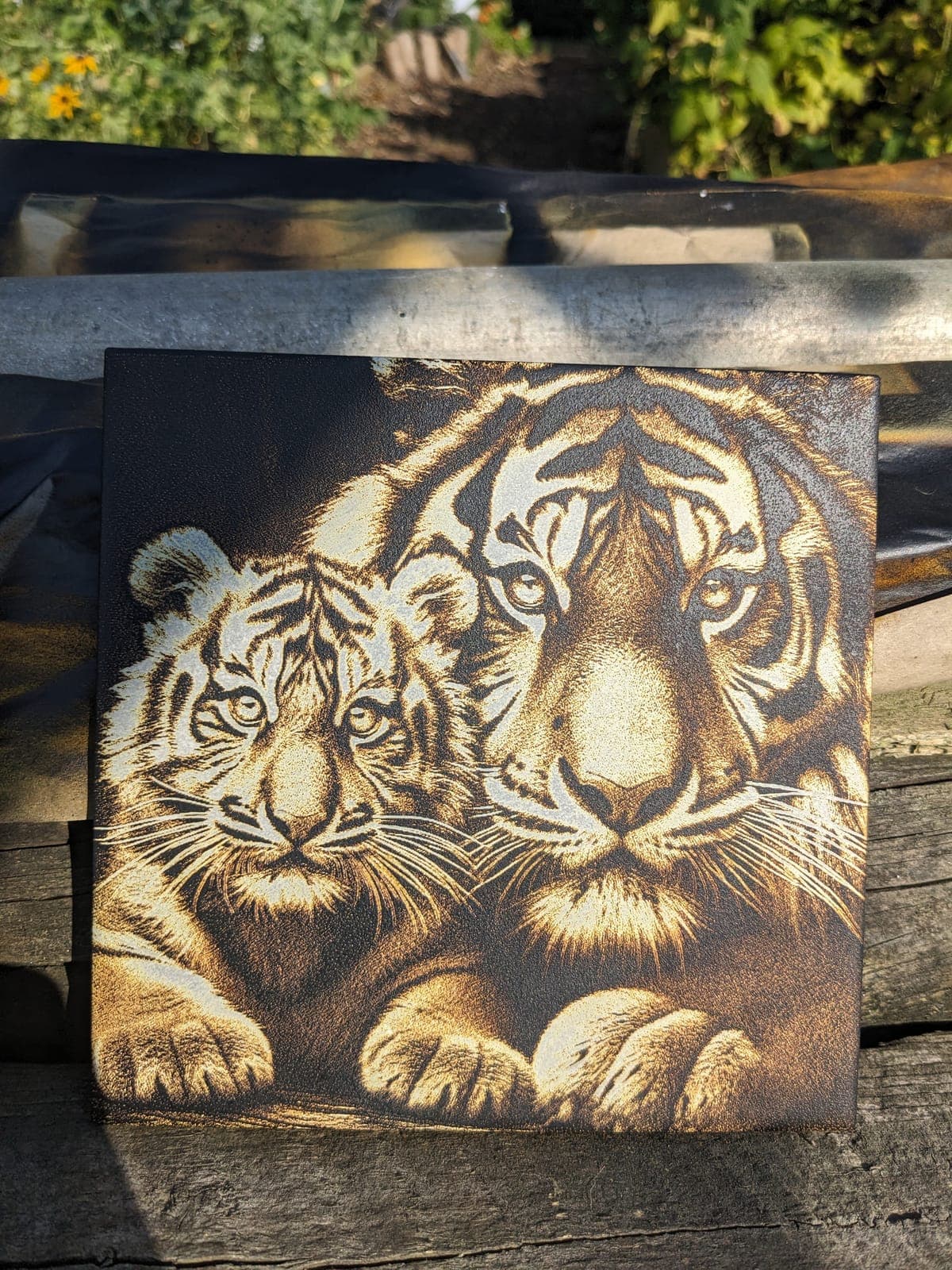A tiger and its cub engraved in warm golden tones on a square tile